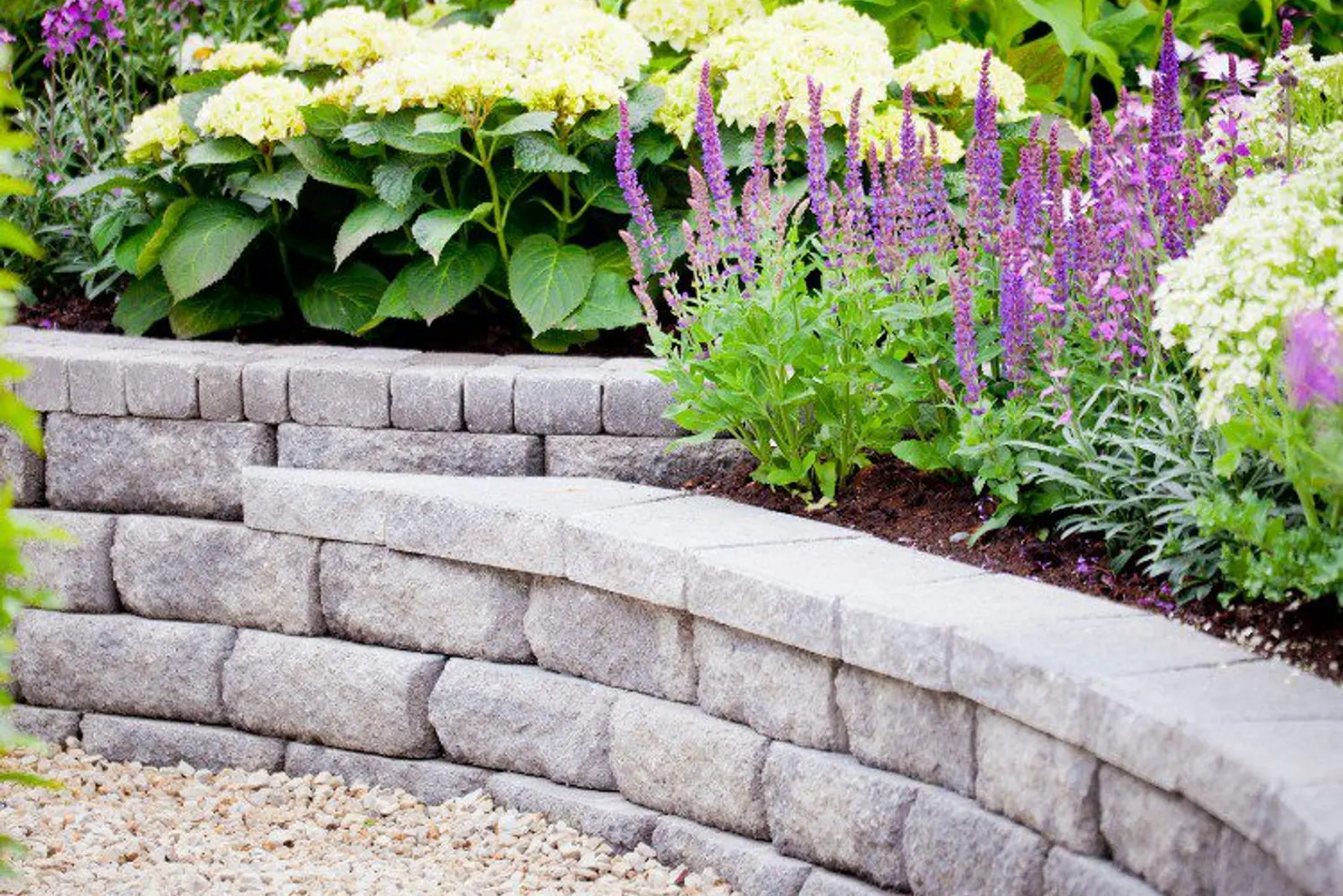 Tiered concrete block retaining wall topped with flowering plants