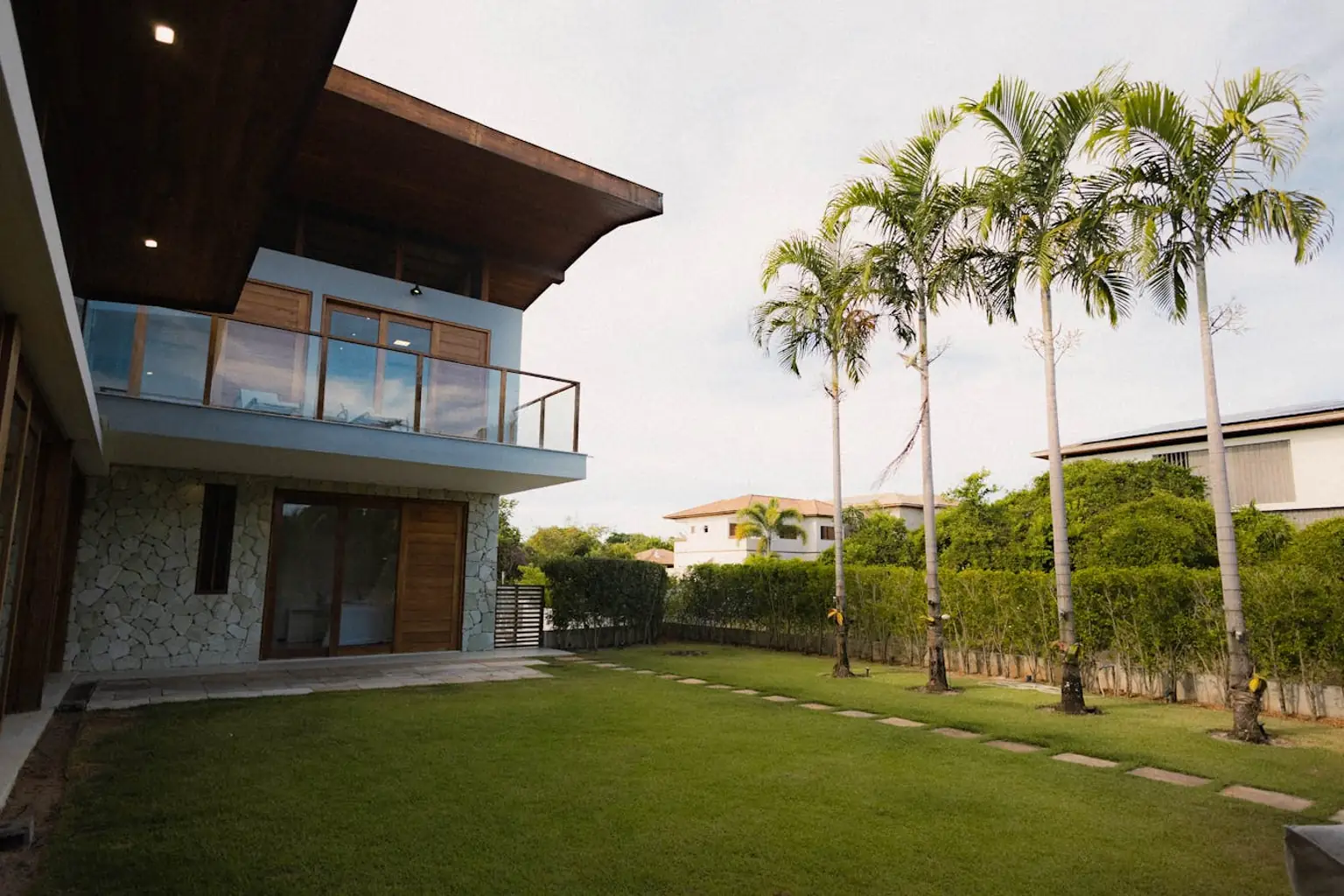 Tropical front-yard turf installation with palm trees and lush curb appeal